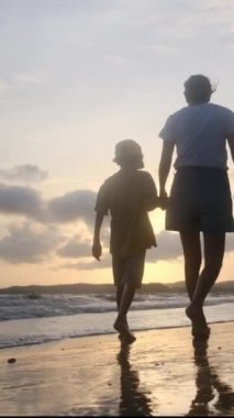 Aile bağının yürek ısıtan özünü bir annenin ve oğullarının sakin bir sahilde büyüleyici bir gün batımının arka planında el ele tutuşmaları gibi yaşayın.