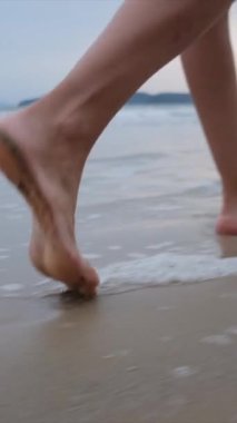  Yaz tatili ya da tatil boyunca kadın bacakları kumda okyanus ya da deniz kenarında yürüyor. Sahilde, doğada ve özgürlükte bir kadın tek başına akıntıda, gelgitte ya da dalgalarda yürür.