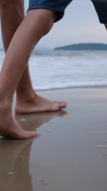 Kadın ve çocuk kumsalda yalınayak yürüyor.