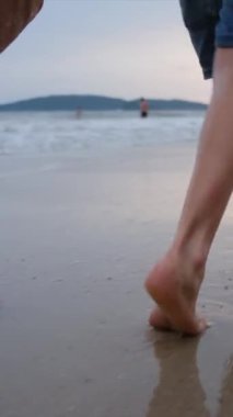 Kadın ve çocuk kumsalda yalınayak yürüyor.