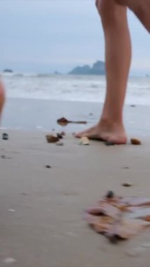 Bir anne ve oğullarının silueti gibi aile bağlantısı sakin bir plajda büyüleyici bir günbatımının arka planında yürüyor.
