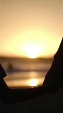 Aile bağının yürek ısıtan özünü, sakin bir sahilde büyüleyici bir günbatımının arka planına karşı el ele tutuşan bir anne ve oğlunun silueti gibi yaşayın.