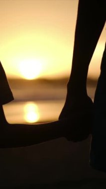 Aile bağının yürek ısıtan özünü, sakin bir sahilde büyüleyici bir günbatımının arka planına karşı el ele tutuşan bir anne ve oğlunun silueti gibi yaşayın.
