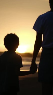 Aile bağının yürek ısıtan özünü, sakin bir sahilde büyüleyici bir günbatımının arka planına karşı el ele tutuşan bir anne ve oğlunun silueti gibi yaşayın.