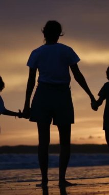 Aile bağının yürek ısıtan özünü bir annenin ve oğullarının sakin bir sahilde büyüleyici bir gün batımının arka planında el ele tutuşmaları gibi yaşayın.