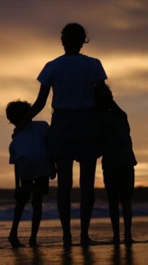 Aile bağının yürek ısıtan özünü bir annenin ve oğullarının sakin bir sahilde büyüleyici bir gün batımının arka planında el ele tutuşmaları gibi yaşayın.