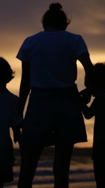 Aile bağının yürek ısıtan özünü bir annenin ve oğullarının sakin bir sahilde büyüleyici bir gün batımının arka planında el ele tutuşmaları gibi yaşayın.