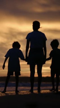 Aile bağının yürek ısıtan özünü bir annenin ve oğullarının sakin bir sahilde büyüleyici bir gün batımının arka planında el ele tutuşmaları gibi yaşayın.