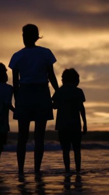 Aile bağının yürek ısıtan özünü bir annenin ve oğullarının sakin bir sahilde büyüleyici bir gün batımının arka planında el ele tutuşmaları gibi yaşayın.