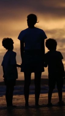 Aile bağının yürek ısıtan özünü bir annenin ve oğullarının sakin bir sahilde büyüleyici bir gün batımının arka planında el ele tutuşmaları gibi yaşayın.