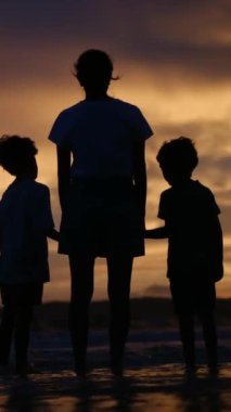 Aile bağının yürek ısıtan özünü bir annenin ve oğullarının sakin bir sahilde büyüleyici bir gün batımının arka planında el ele tutuşmaları gibi yaşayın.