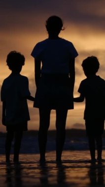 Aile bağının yürek ısıtan özünü bir annenin ve oğullarının sakin bir sahilde büyüleyici bir gün batımının arka planında el ele tutuşmaları gibi yaşayın.