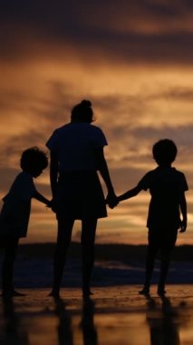 Aile bağının yürek ısıtan özünü bir annenin ve oğullarının sakin bir sahilde büyüleyici bir gün batımının arka planında el ele tutuşmaları gibi yaşayın.