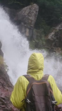 Dağlarda yürüyüş yapan kadın şelaleye bakıyor. 