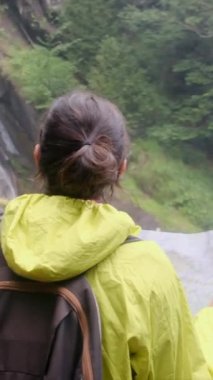 Dağlarda yürüyüş yapan kadın şelalenin yakınındaki haritaya bakıyor. 