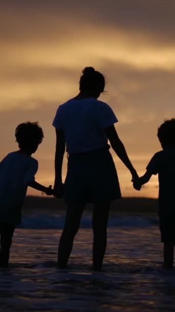 在宁静的海滩上 在迷人的落日的映衬下 母亲和儿子手牵着手 感受着家庭联系温暖的本质 — 图库视频影像