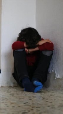 Üzgün çocuk, eski püskü duvarların yanında dizlerinin üzerinde oturuyor.