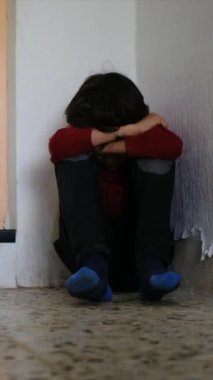 Üzgün çocuk, eski püskü duvarların yanında dizlerinin üzerinde oturuyor.