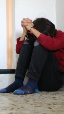 Üzgün çocuk, eski püskü duvarların yanında dizlerinin üzerinde oturuyor.