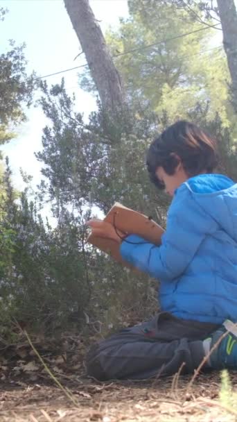 Chłopiec Robi Notatki Swoim Notatniku Lesie — Wideo stockowe