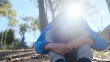 Üzgün çocuk dışarıda, dizlerinin üzerinde oturuyor.