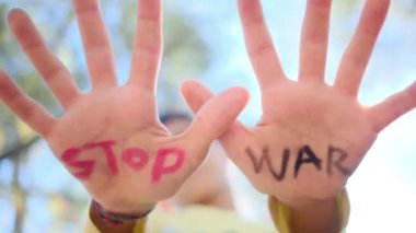 Avuç içlerindeki savaş kelimelerini durduran çocuk, yakın plan.