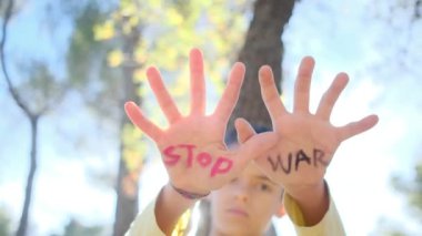 Avuç içlerindeki savaş kelimelerini durduran çocuk, yakın plan.