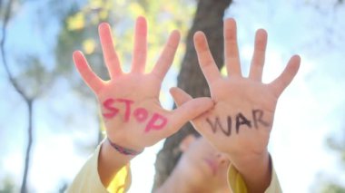 Avuç içlerindeki savaş kelimelerini durduran çocuk, yakın plan.