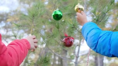 Kardeşler dışarıda Noel ağacı süslüyorlar.