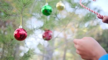 Çocuk dışarıda Noel ağacı süslüyor.