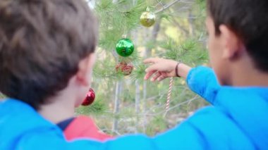 Kardeşler dışarıda Noel ağacı süslüyorlar.