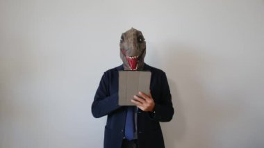 Dinozor maskeli bir işadamı tableti kapalı bir yerde tutuyor.