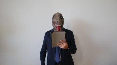 Dinozor maskeli bir işadamı tableti kapalı bir yerde tutuyor.