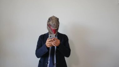 Akıllı telefonlu dinozor maskeli bir iş adamı.