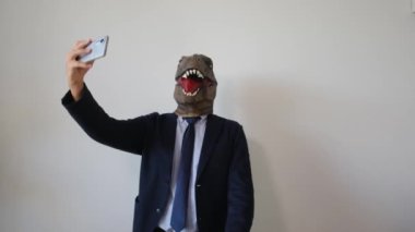 Dinozor maskeli bir iş adamı içeride selfie akıllı telefonlardan konuşuyor.