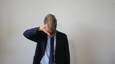 Başparmağı aşağıda, dinozor maskeli bir iş adamı. 