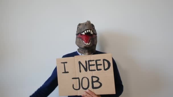 戴着恐龙面具的商人拿着印有文字的卡片我需要在工作室工作 — 图库视频影像