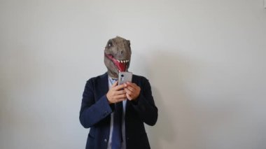 Akıllı telefonlu dinozor maskeli bir iş adamı.