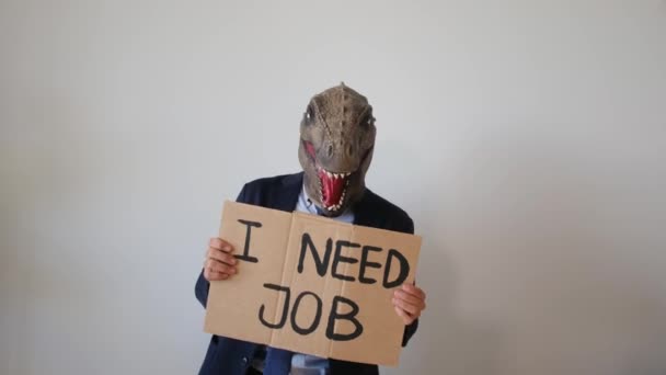 スタジオで仕事が必要なテキスト付きのカードを示す恐竜のマスクを着ているビジネスマン — ストック動画