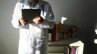 Klinikte elinde tablet bilgisayar tutan bir doktor.
