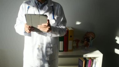 Klinikte elinde tablet bilgisayar tutan bir doktor.
