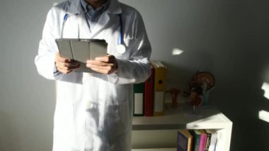 Klinikte elinde tablet bilgisayar tutan bir doktor.