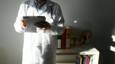 Klinikte elinde tablet bilgisayar tutan bir doktor.