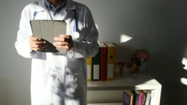 Klinikte elinde tablet bilgisayar tutan bir doktor.