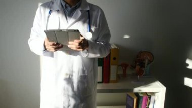 Klinikte elinde tablet bilgisayar tutan bir doktor.