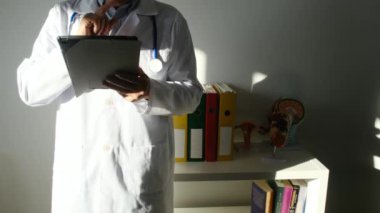 Klinikte elinde tablet bilgisayar tutan bir doktor.