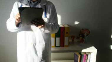Klinikte elinde tablet bilgisayar tutan bir doktor.