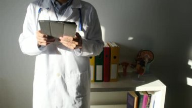 Klinikte elinde tablet bilgisayar tutan bir doktor.