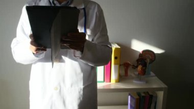 Klinikte elinde tablet bilgisayar tutan bir doktor.