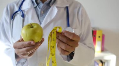 Elma tutan ve mezura kullanan genç bir doktor. 